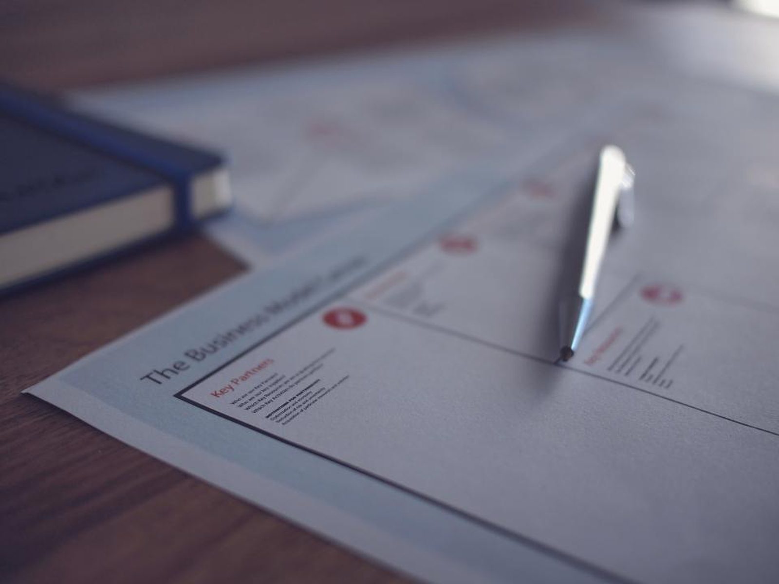 A recorded document open on a desk with a pen resting on it, mid-read